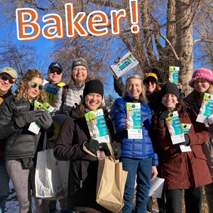 Group of smiling people wearing hats and gloves, with blue sky and leafless trees, behind them. They're holding up flyers that say Denver Digs Trees